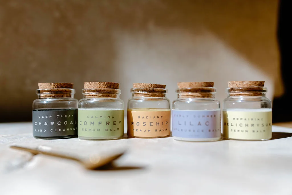 Five serum balms in corked jars — charcoal, comfrey, rosehip, lilac and helichrysum